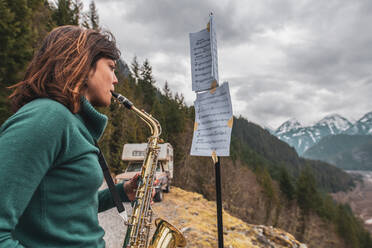 Eine Frau steht auf einem Berg im Squamish Valley, British Columbia, Kanada, und spielt Saxophon. - ISF24189
