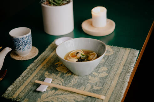 Nahaufnahme einer Schüssel Suppe mit Knödeln in einem Ramen- und Gyoza-Restaurant in Italien. - ISF24217