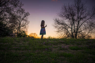 Kleines Mädchen hält Blume silohette lange Haare Sommerabend Sonnenuntergang - CAVF84465