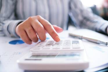 Cropped Image Of Businessman Calculating With Calculator At Desk In Office - EYF05056