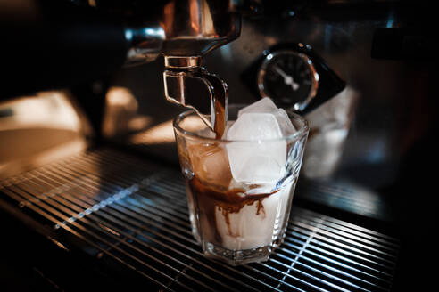 Nahaufnahme von Kaffee gießt in Trinkglas im Café - EYF05076