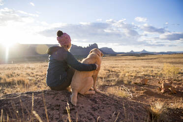 Eine Frau und ihr gelber Labrador genießen einen wunderschönen Sonnenuntergang in der Wüste. - CAVF84494