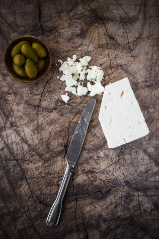 Feta-Käse, Schale mit frischen Oliven und Tafelmesser auf Holzunterlage, lizenzfreies Stockfoto