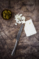 Feta-Käse, Schale mit frischen Oliven und Tafelmesser auf Holzunterlage - GIOF08350