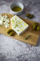 Schneidebrett mit Feta-Käse und Oliven - GIOF08358