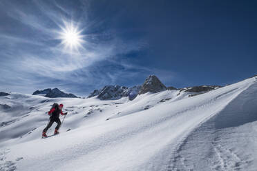 Mann beim Skifahren auf dem schneebedeckten Dachstein gegen den Himmel an einem sonnigen Tag, Österreich - HAMF00628