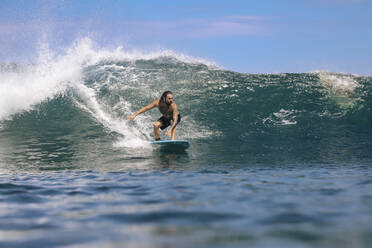 Männlicher Surfer ohne Hemd, der auf dem Meer gegen den Himmel surft, Bali, Indonesien - KNTF04669