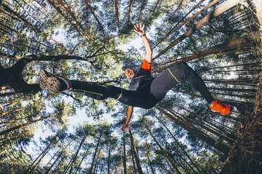 Älterer Mann springt gegen Bäume im Wald - OCMF01345