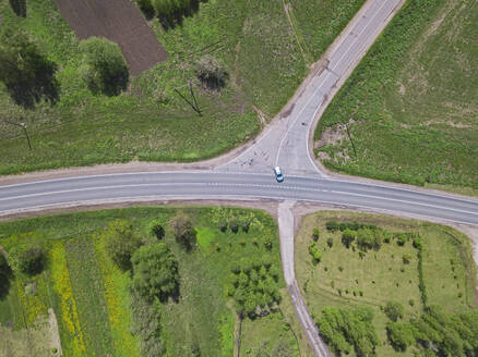 Russland, Oblast Moskau, Luftaufnahme eines Autos, das auf einer Landstraße an einer Kreuzung vorbeifährt - KNTF04675