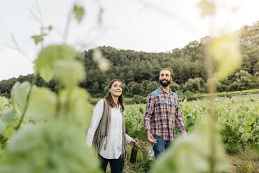 Lächelndes Paar mit Weingläsern und Weinflasche in einem Weinberg - JRFF04485