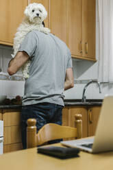 Mann trägt Hund beim Kochen in der Küche - XLGF00180