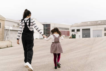 Mother and daughter holding hands while walking on street - EGAF00131