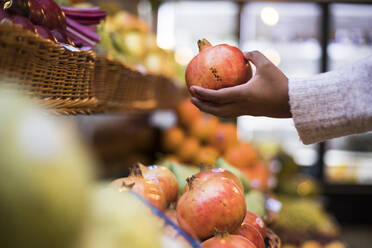 Cropped image of woman buying pomegranate at grocery store - ABZF03175