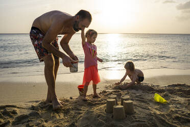 Vater spielt mit seinen Kindern am Strand bei Sonnenuntergang, Willemstad, Curacao - JLOF00421