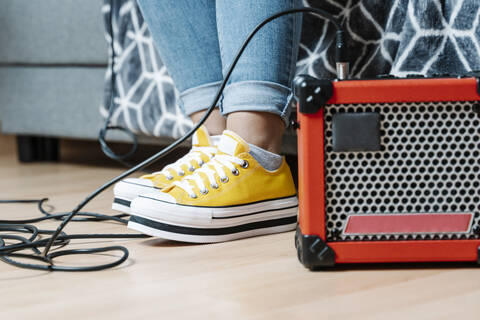 Woman's legs by amplifier on hardwood floor at home stock photo