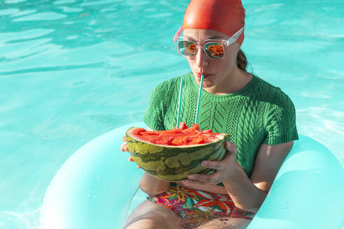 Porträt einer Frau mit Schwimmreifen und Wassermelone im Schwimmbad - ERRF03975