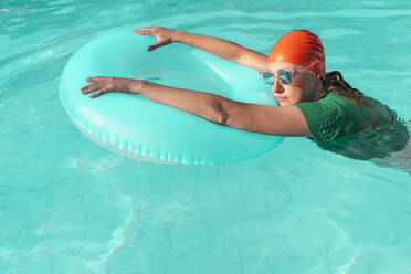 Porträt einer Frau mit roter Badekappe, grünem Strickpullover und verspiegelter Sonnenbrille im Schwimmbad - ERRF03986