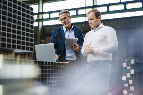 Zwei Geschäftsleute bei einer Besprechung in einer Fabrik mit Laptop - MOEF02894