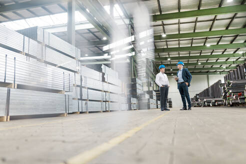 Zwei Geschäftsleute unterhalten sich in einer Fabrik - MOEF02897