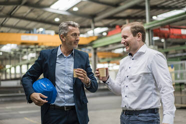 Zwei Geschäftsleute machen eine Kaffeepause in einer Fabrik - MOEF02909