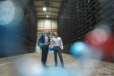 Two businessmen in a high rack warehouse of a factory - MOEF02924