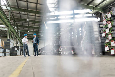 Two businessmen talking in a factory - MOEF02930