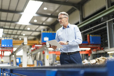 Mature businessman using tablet in a factory - MOEF02932