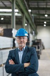 Porträt eines reifen Geschäftsmannes mit Schutzhelm und Schutzbrille in einer Fabrik - MOEF02946