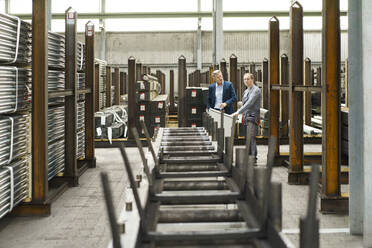 Businessman talking to worker in a factory - MOEF02949