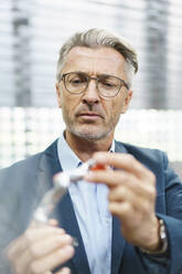 Portrait of mature businessman examining industrial product - MOEF02990