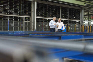 Zwei Geschäftsleute mit Tablet im Gespräch in einer Fabrik - MOEF02998