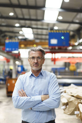 Porträt eines selbstbewussten reifen Geschäftsmannes in einer Fabrik, lizenzfreies Stockfoto