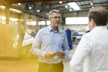 Two businessmen having a meeting in a factory - MOEF03010