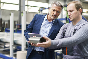 Geschäftsmann und Arbeiter bei der Prüfung von Stahlrohren in einer Fabrik - MOEF03022