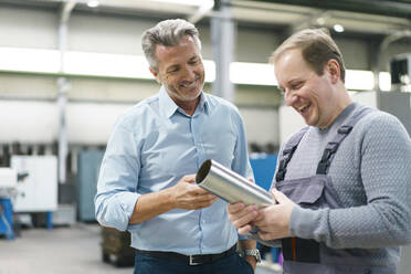 Glücklicher Geschäftsmann und Arbeiter bei der Prüfung von Stahlrohren in einer Fabrik - MOEF03024