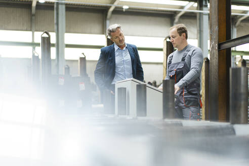 Geschäftsmann im Gespräch mit einem Arbeiter an einer Maschine in einer Fabrik - MOEF03039