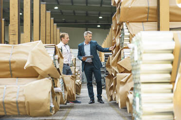 Two businessmen in a factory storehouse with steel pipes - MOEF03071