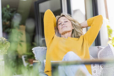 Porträt einer reifen Frau mit geschlossenen Augen, die sich auf einer Terrasse entspannt - UUF20537