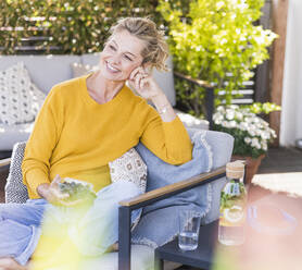Porträt einer glücklichen reifen Frau, die sich auf einer Terrasse entspannt - UUF20546