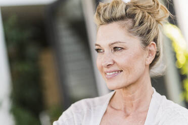 Portrait of smiling mature woman relaxing on terrace - UUF20563