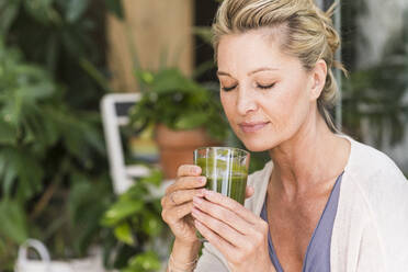 Portrait of mature woman with eyes closed with glass of green smoothie - UUF20568