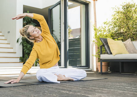 Mature woman doing yoga exercise on terrace - UUF20576