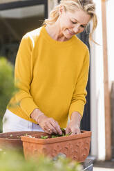 Smiling mature woman gardening on terrace - UUF20582