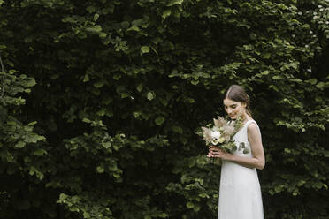 Junge Frau in elegantem Hochzeitskleid und Blumenstrauß - ALBF01271