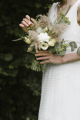 Junge Frau in elegantem Hochzeitskleid mit Blumenstrauß - ALBF01272