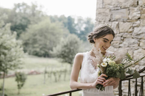 Junge lächelnde Frau in elegantem Hochzeitskleid und Blumenstrauß, lizenzfreies Stockfoto