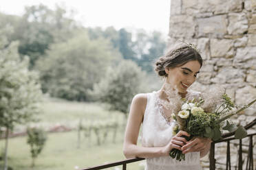 Junge lächelnde Frau in elegantem Hochzeitskleid und Blumenstrauß - ALBF01281