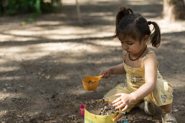 Kleines Mädchen spielt mit Erde in einem Park - VABF03010