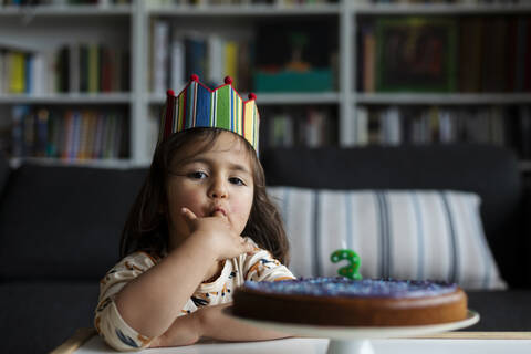 Porträt eines kleinen Mädchens, das einen Geburtstagskuchen probiert, lizenzfreies Stockfoto