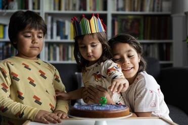 Portrait of little girl celebrating birthday with her older brothers at home - VABF03020